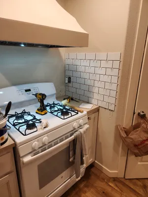 Subway tile backsplash going up behind a range