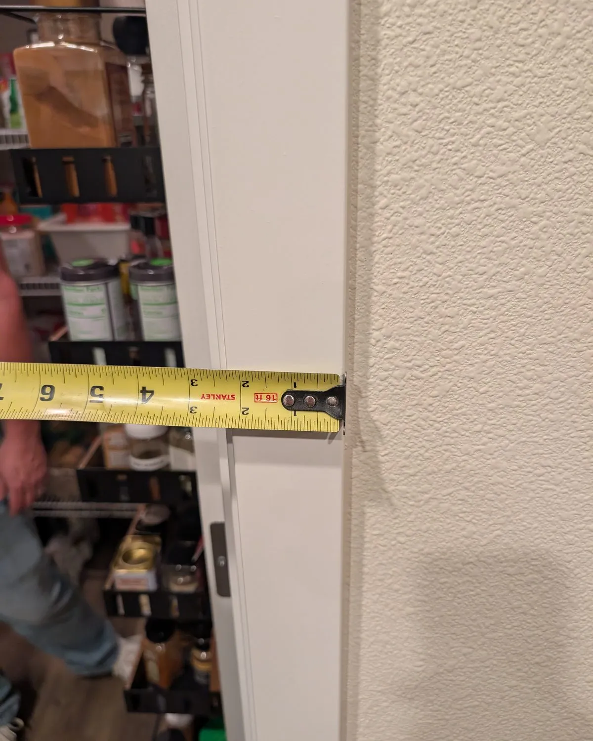 A tape measure held across the trim of a pantry door.